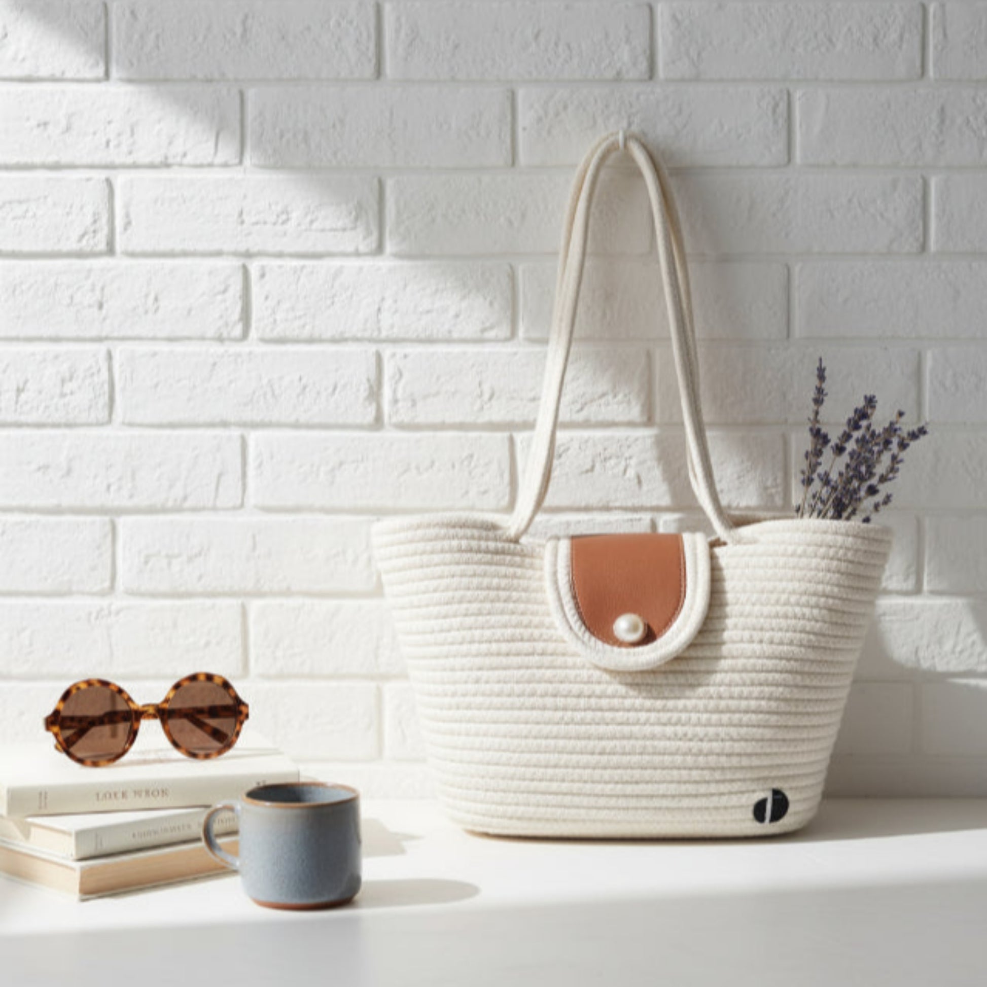 White woven tote bag on a white surface with a white brick wall  - background - dotflakes