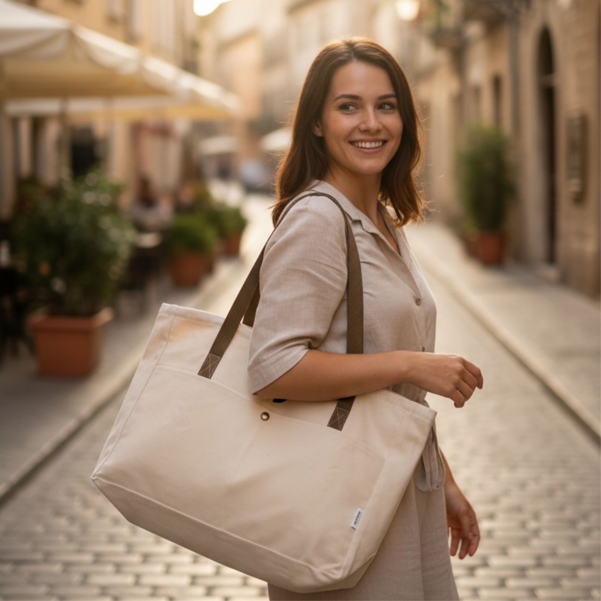 Woman holding a beige tote bag on a street in a european small town - Dotflakes